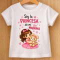 Camiseta infantil blanca para niña con diseño de niña con vestido rosa y osito y frase Soy la princesa de mi madrina